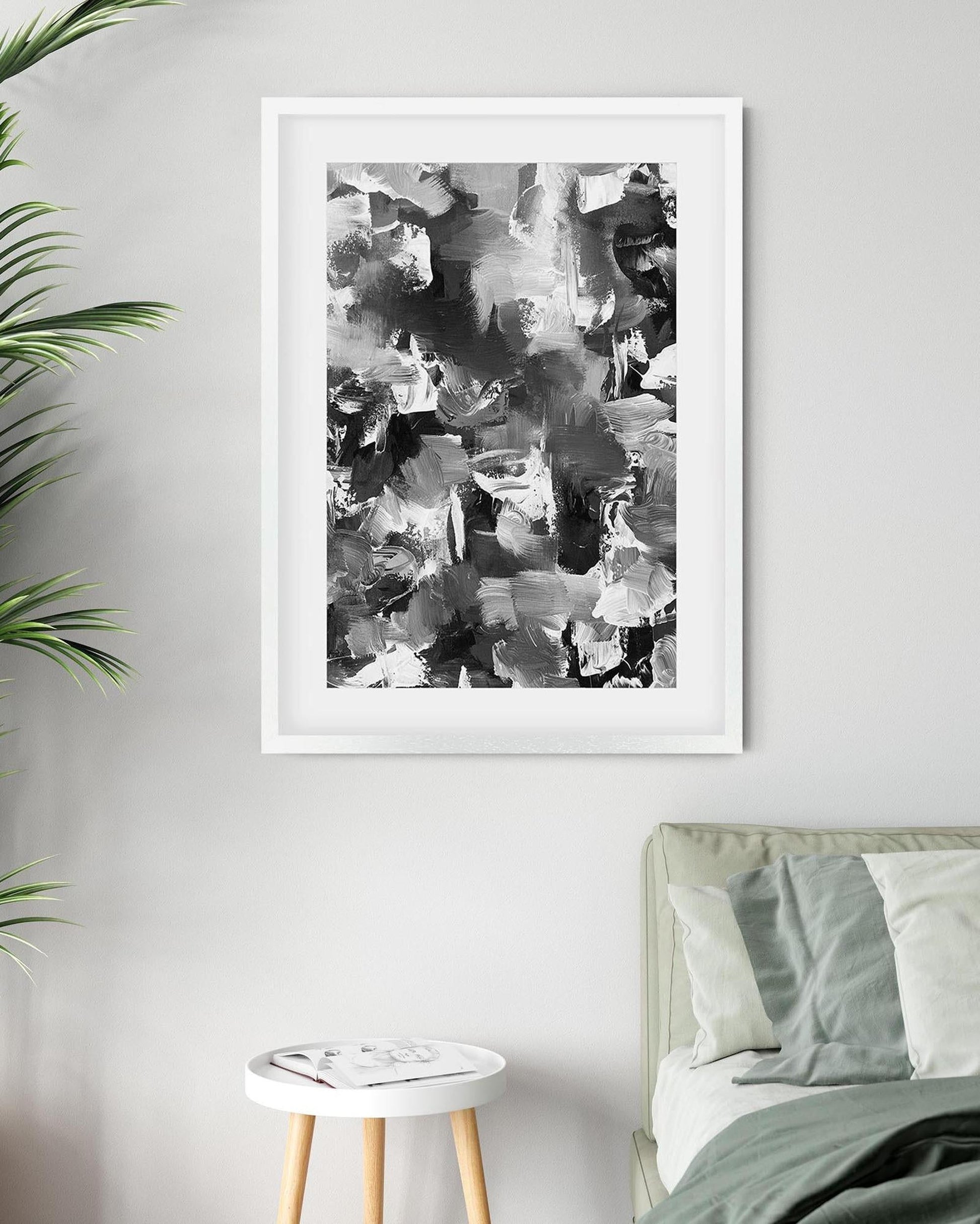 Framed abstract art print on a wall above a bed in a bedroom.