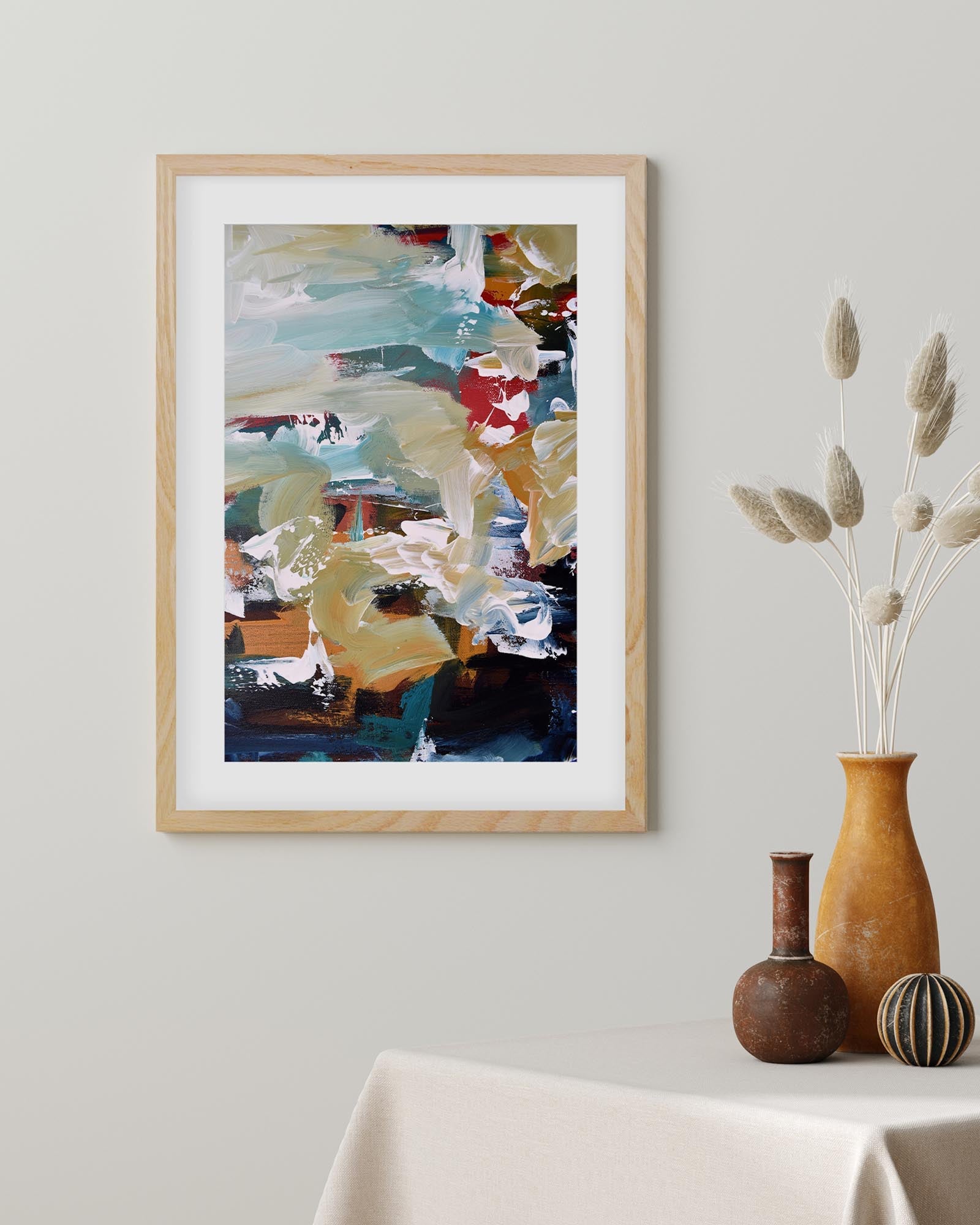Framed abstract painting on a wall with decorative vases below.