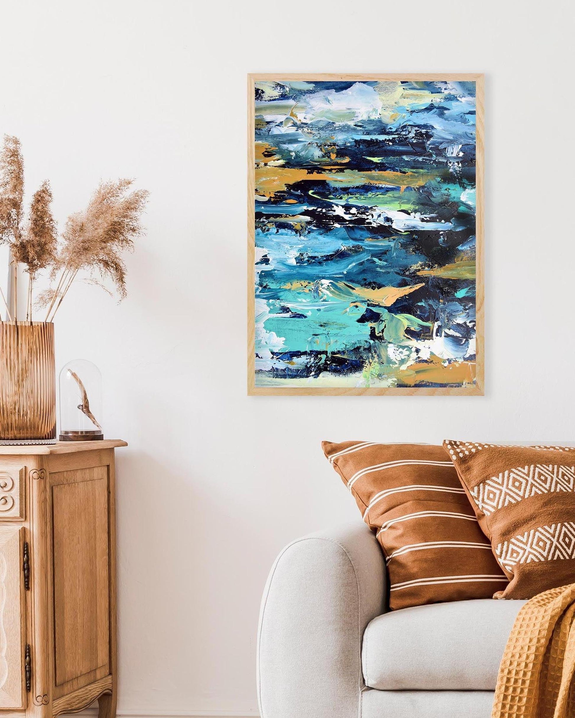 Abstract painting on a wall above a sofa with decorative pillows and a vase.