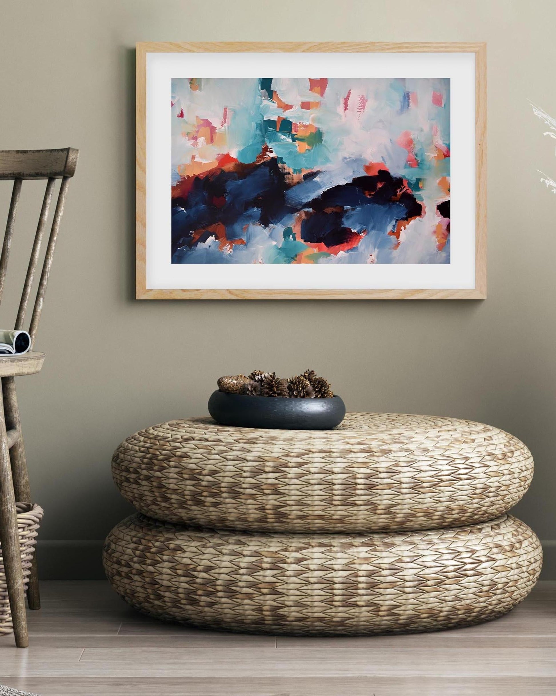 Woven ottoman in front of a wall with a colorful abstract painting