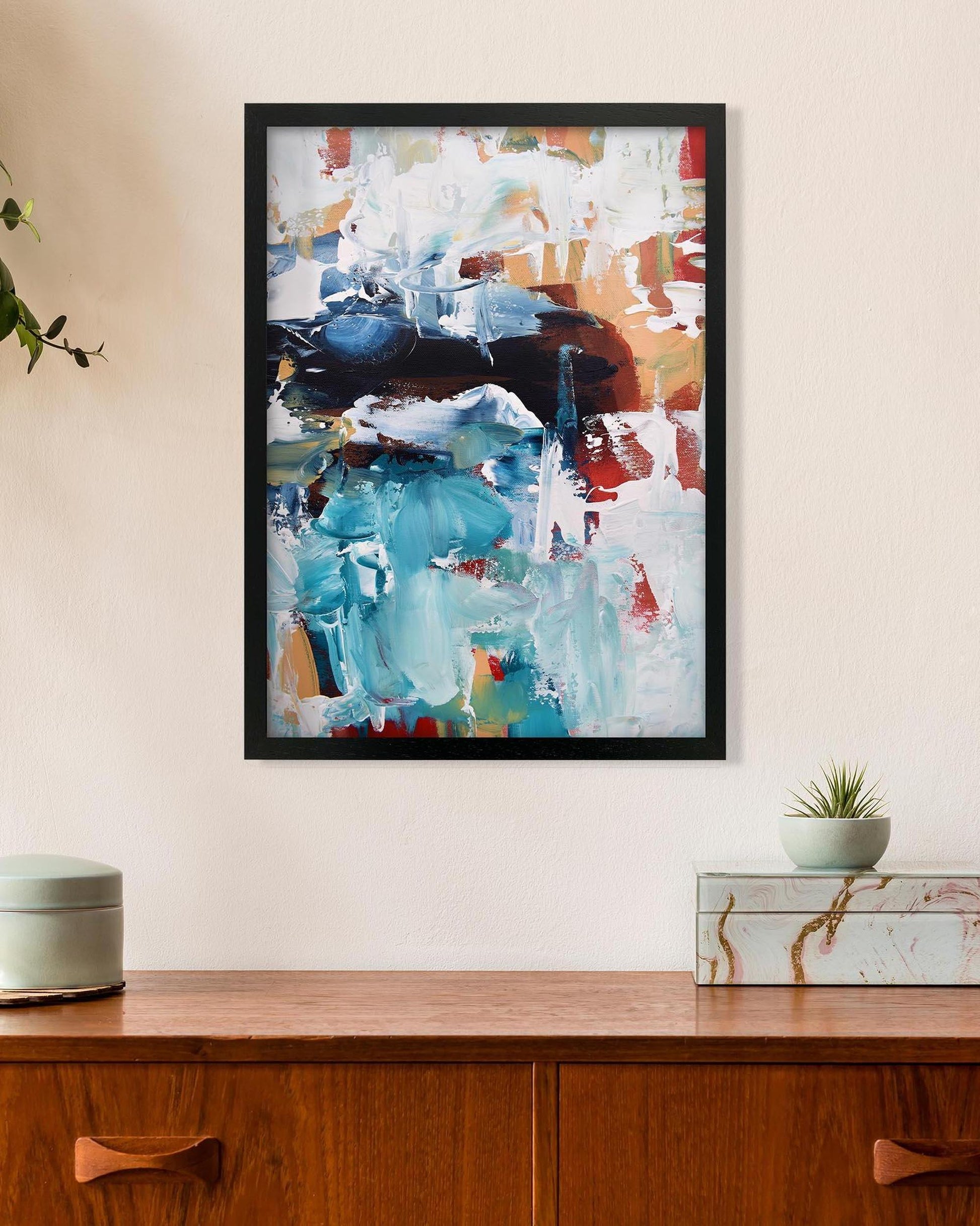 Framed abstract painting on a wall above a wooden console table.
