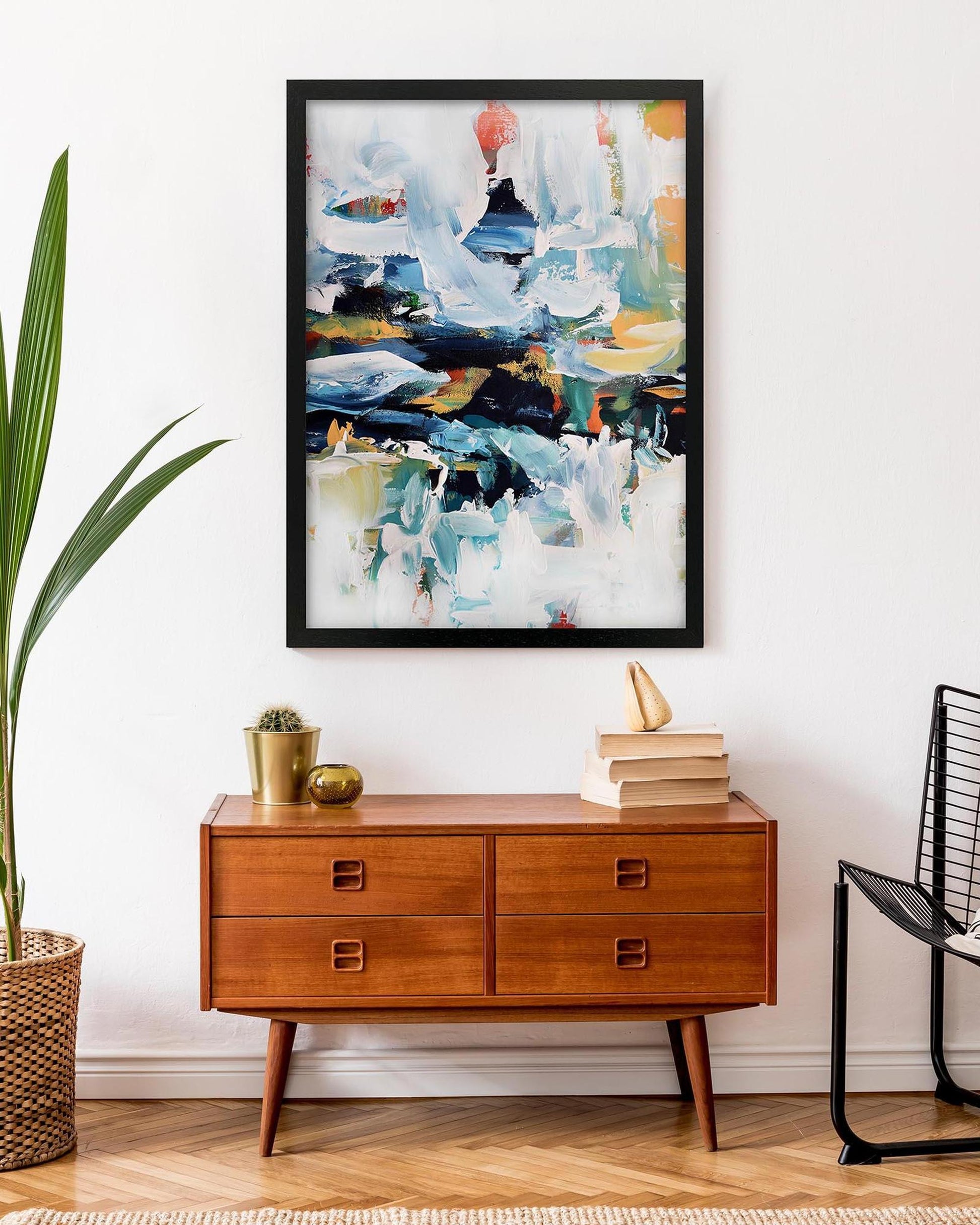 Abstract painting on a wall above a wooden dresser with decor items.