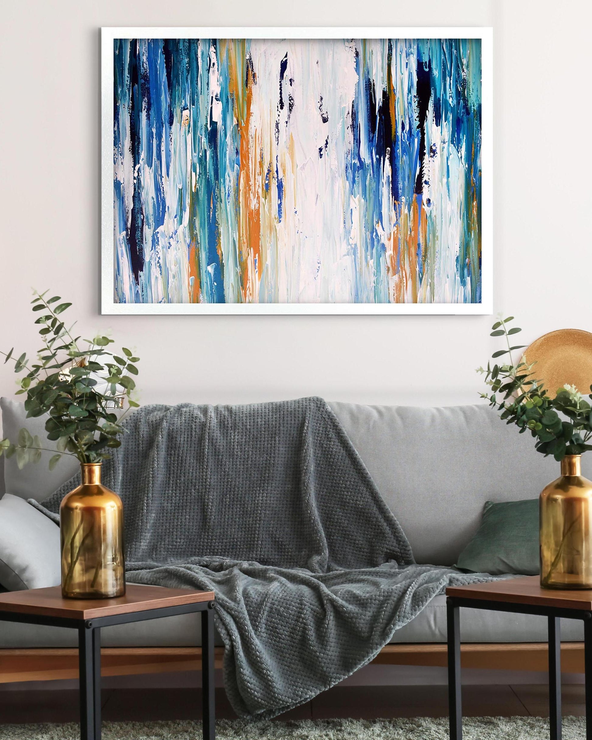 Abstract painting on a wall above a gray sofa with decorative elements.