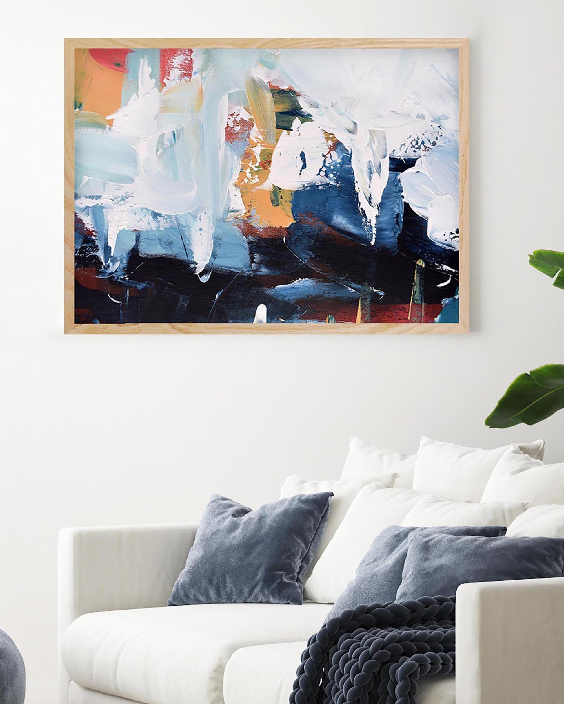 Abstract painting on a wall above a white sofa with blue pillows