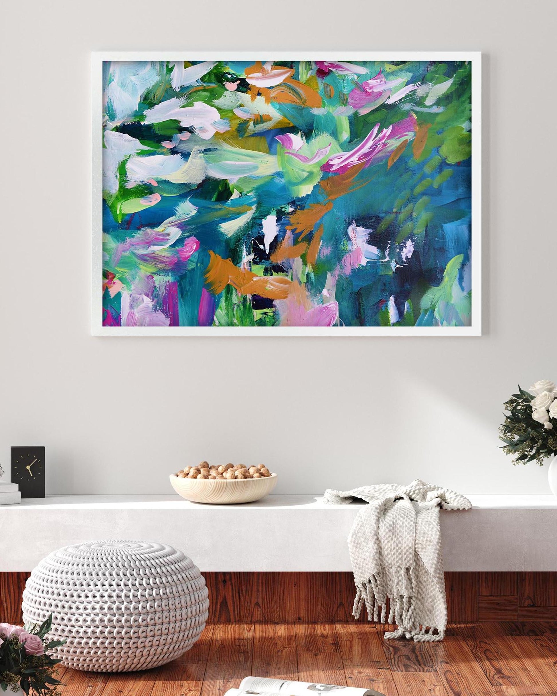 Colorful abstract painting on a wall above a white console table with decorative items.