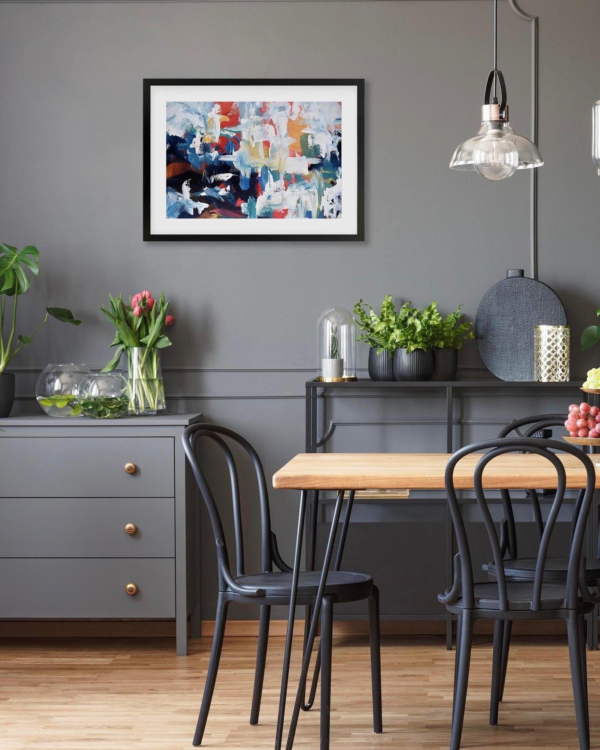 Dining room with a wooden table, black chairs, and abstract art on the wall.