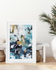 Framed abstract art print in a living room setting with a plant and furniture.