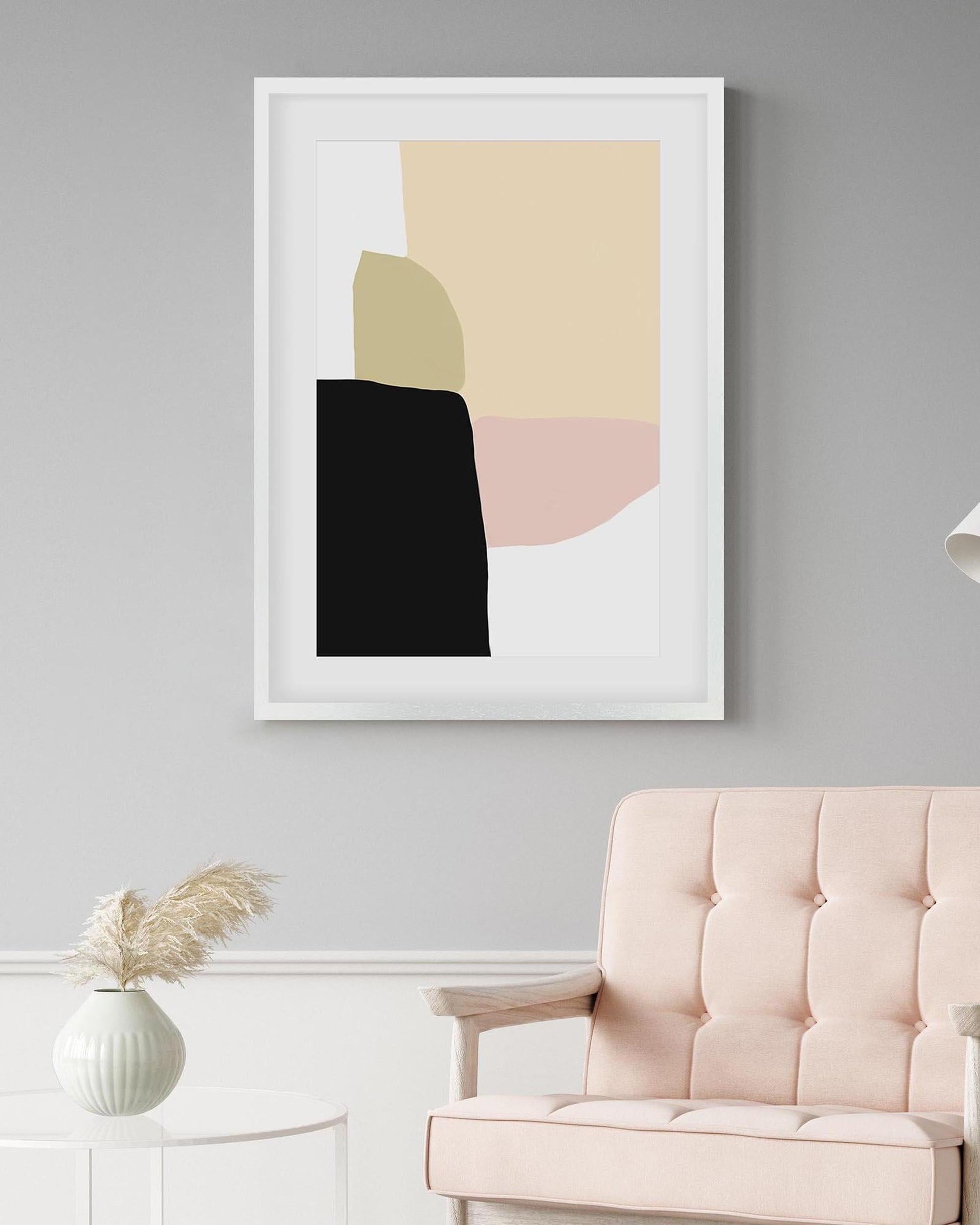 Framed abstract art piece on a gray wall with a pink chair and white cabinet in the foreground.