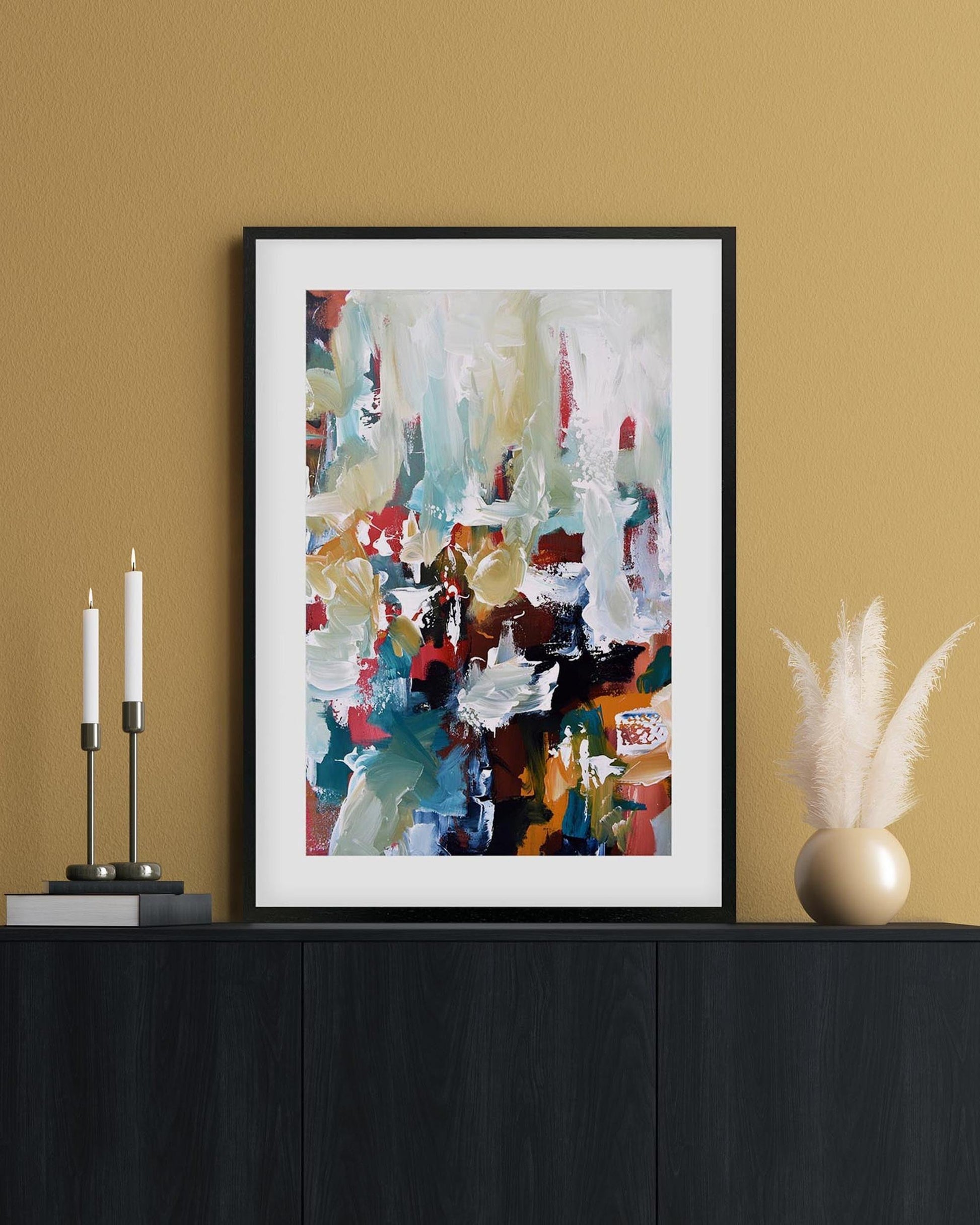 Framed abstract art piece on a black cabinet against a beige wall