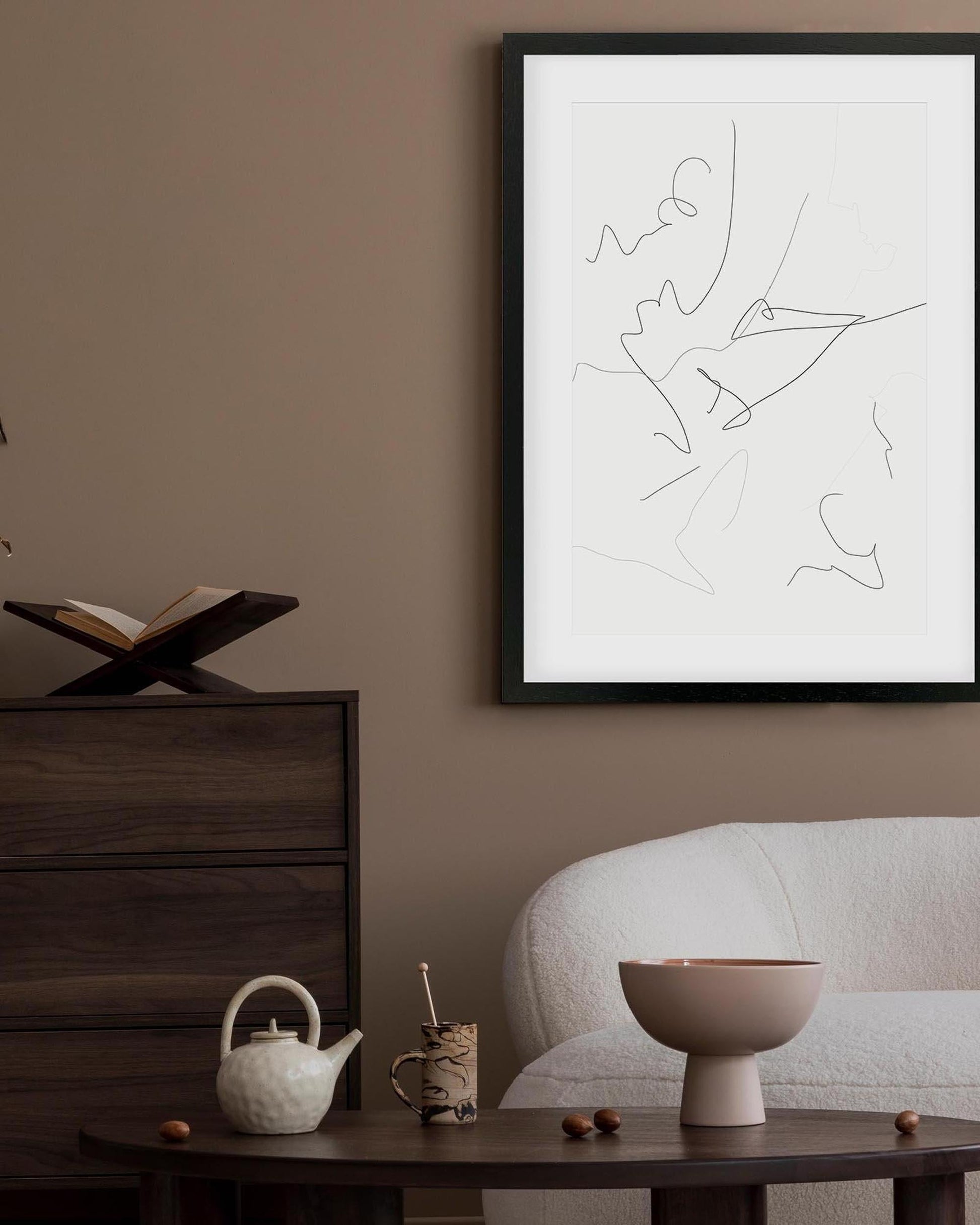 Framed abstract artwork on a wall above a table with decorative items.