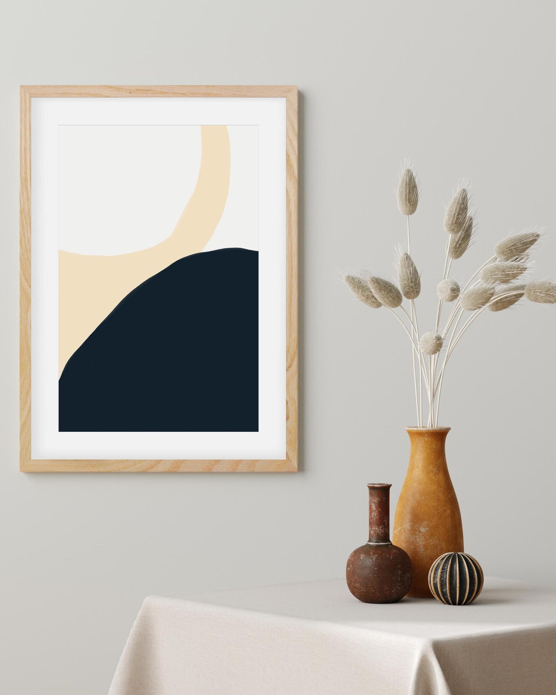 Framed abstract art print on a wall with decorative vases below.