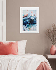Framed abstract art above a bed with pink pillows and a vase on a nightstand.