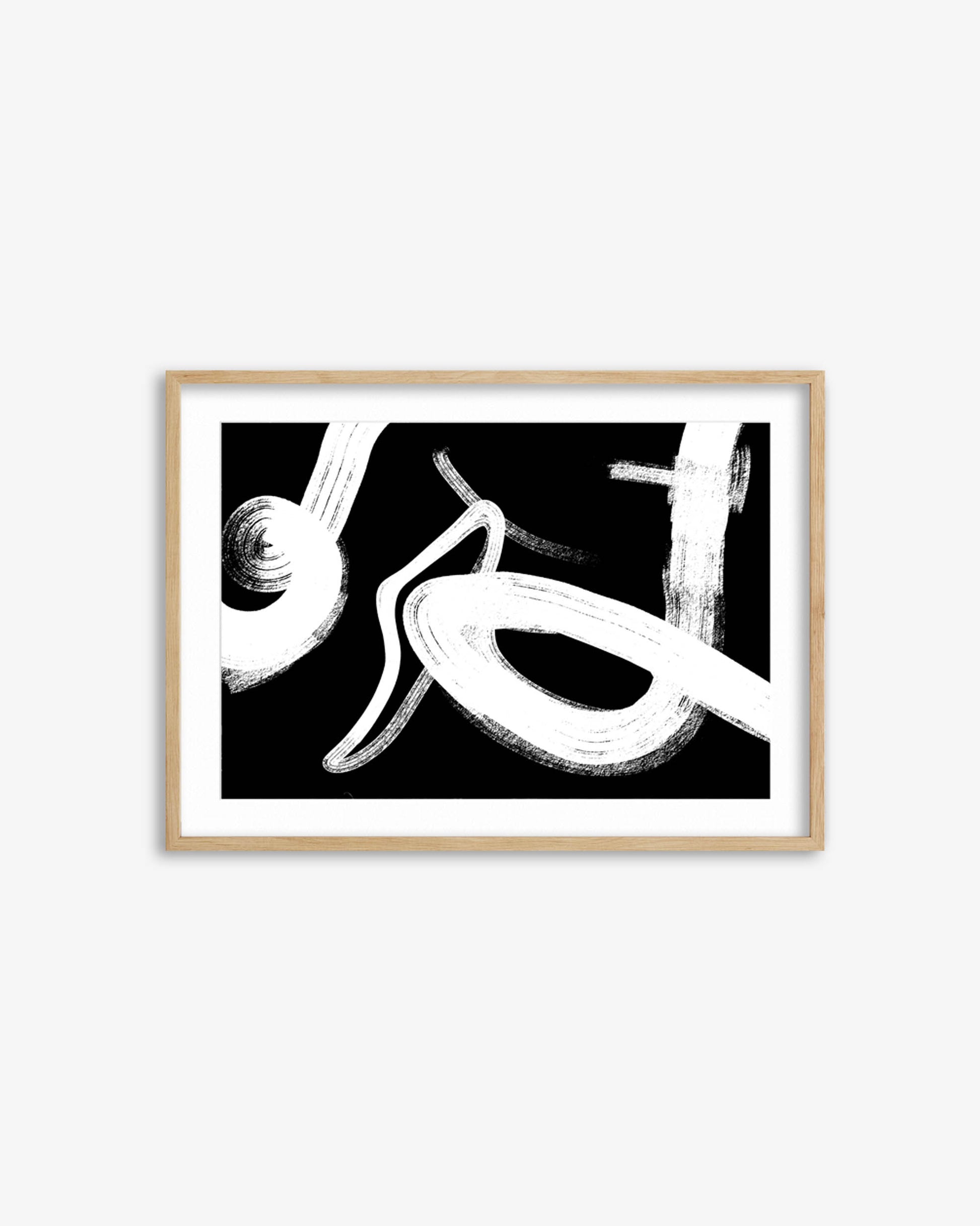 Framed abstract art print with black and white brush strokes on a white wall.