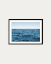 Framed artwork of a blue ocean scene on a white wall
