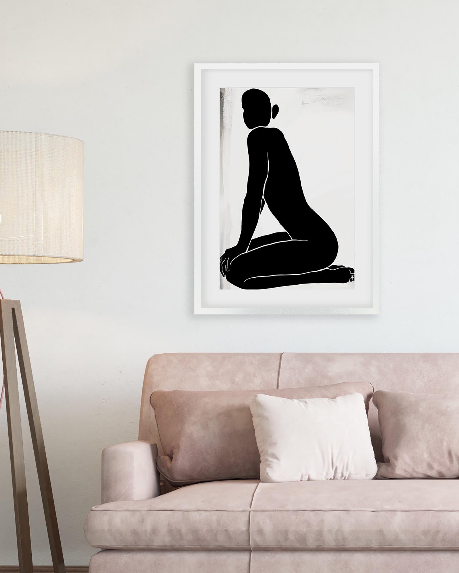 Framed black and white silhouette art print above a beige sofa in a living room.