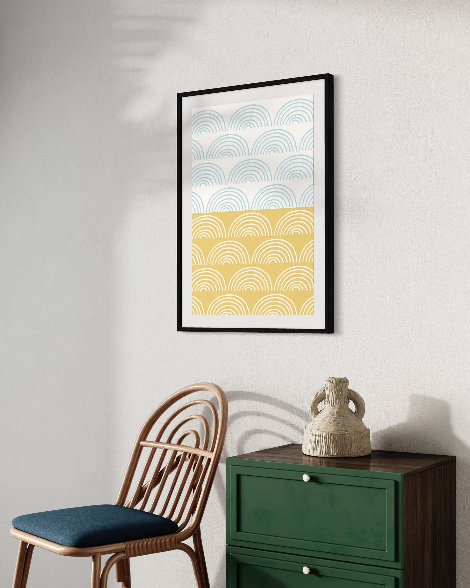 Framed abstract art print on a wall with a chair and green cabinet below.