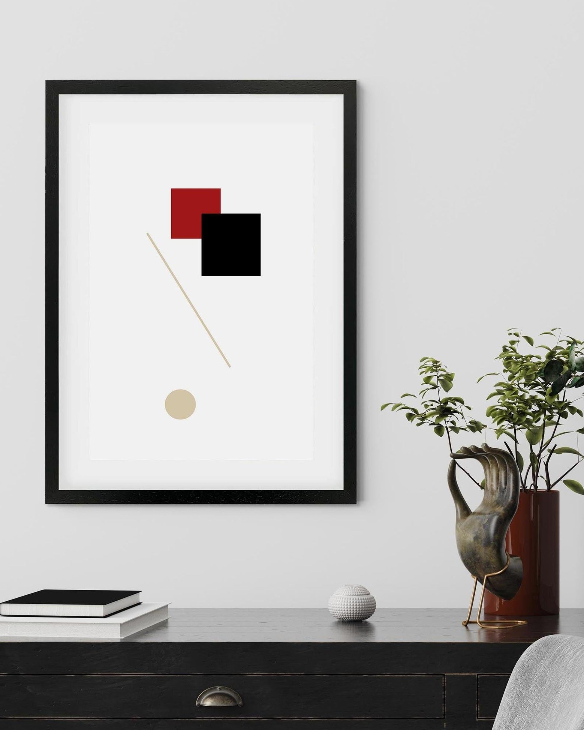 Framed abstract art piece on a wall with decorative items below.