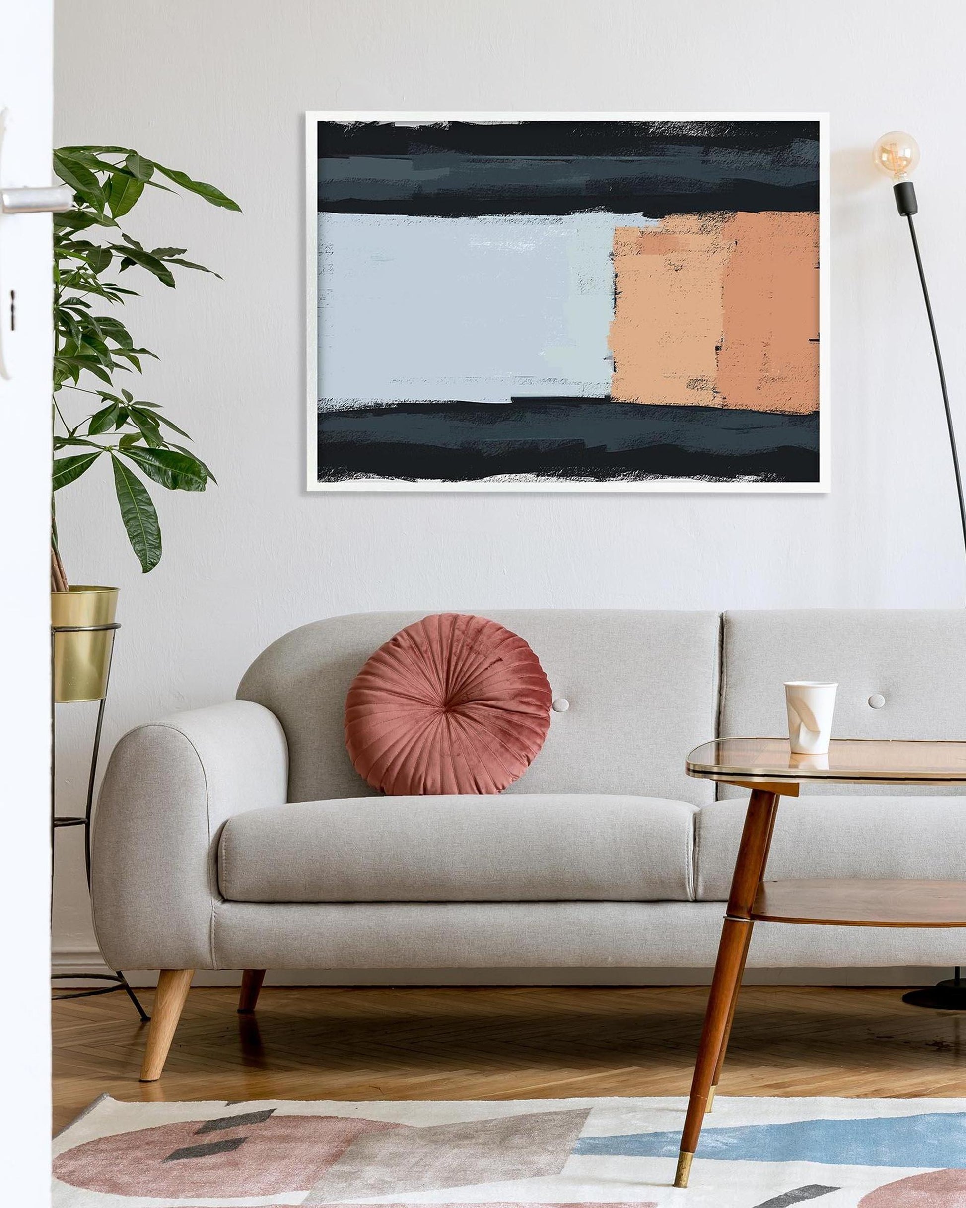 Modern living room with a gray sofa, pink pillow, and abstract painting on the wall.