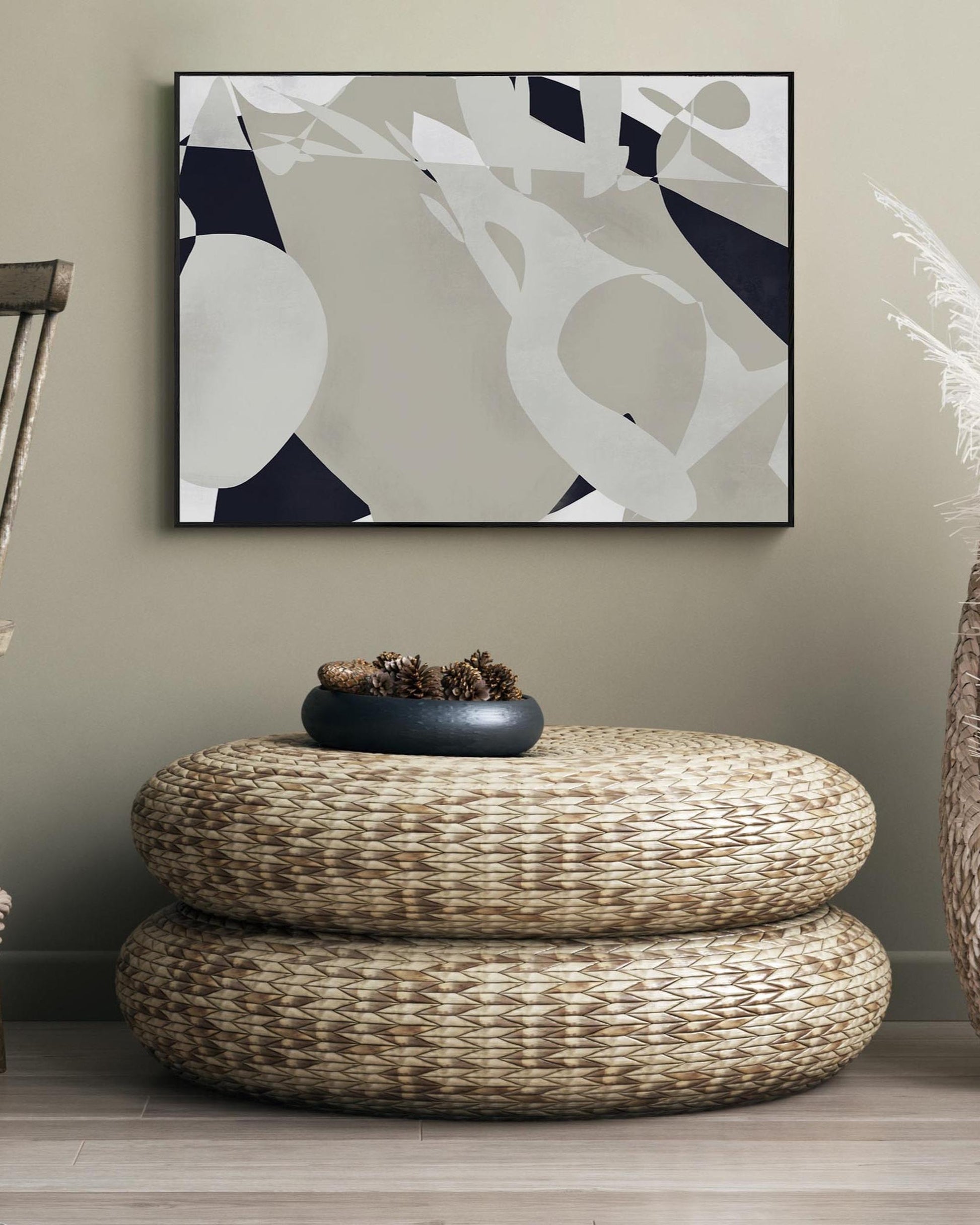 Woven ottoman with decorative items in a room with abstract art on the wall.