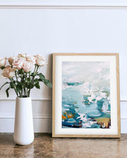 Framed abstract art print on a wall next to a vase with flowers