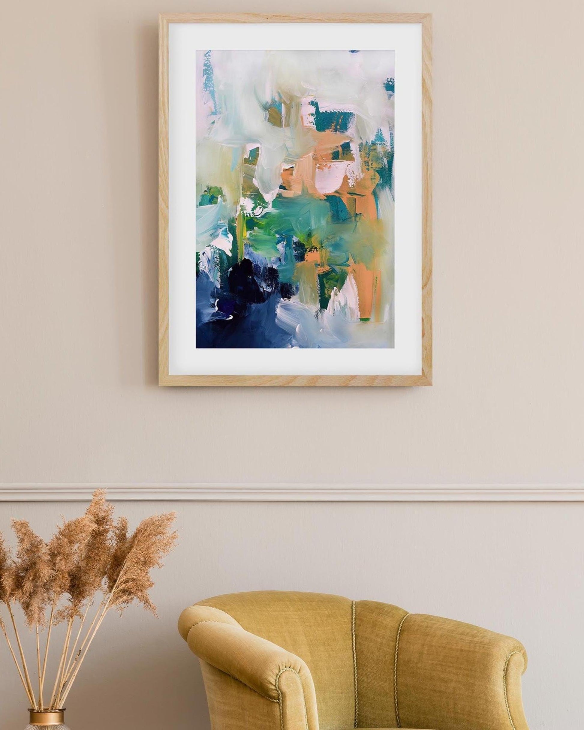 Framed abstract art piece on a wall above a yellow armchair with decorative elements.