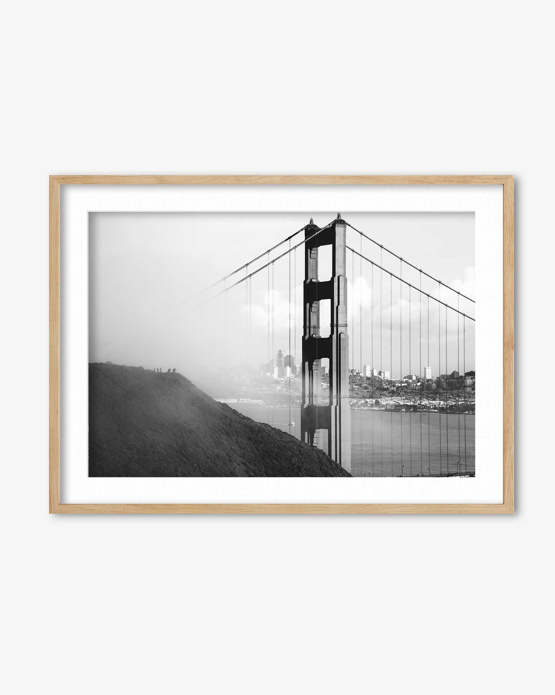 Framed black and white photograph of the Golden Gate Bridge on a white wall.