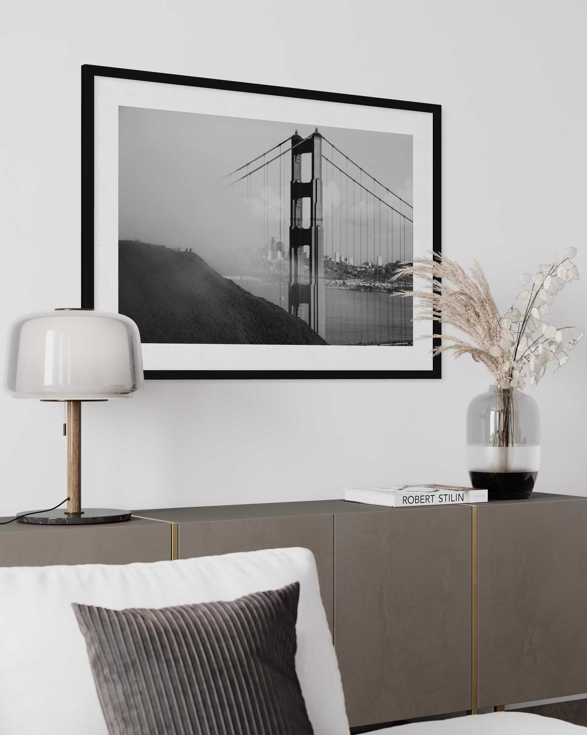 Framed black and white artwork of a bridge on a wall above a sofa.