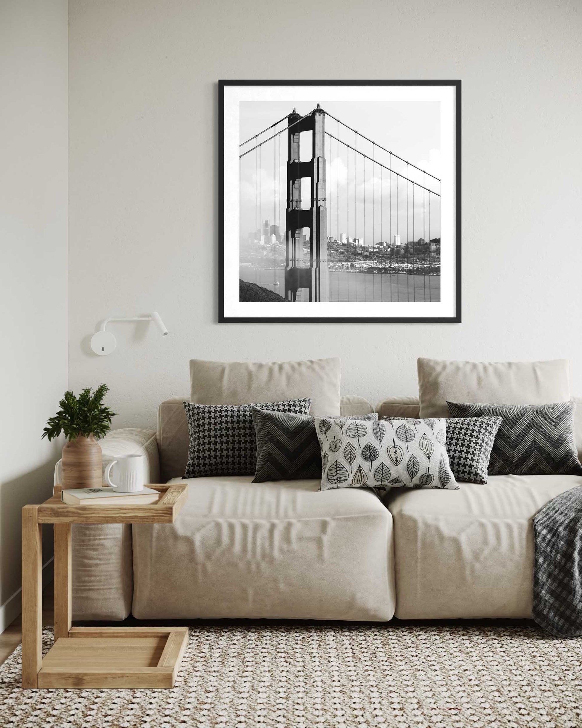 Living room with a beige sofa, wooden side table, and framed picture of the Golden Gate Bridge.