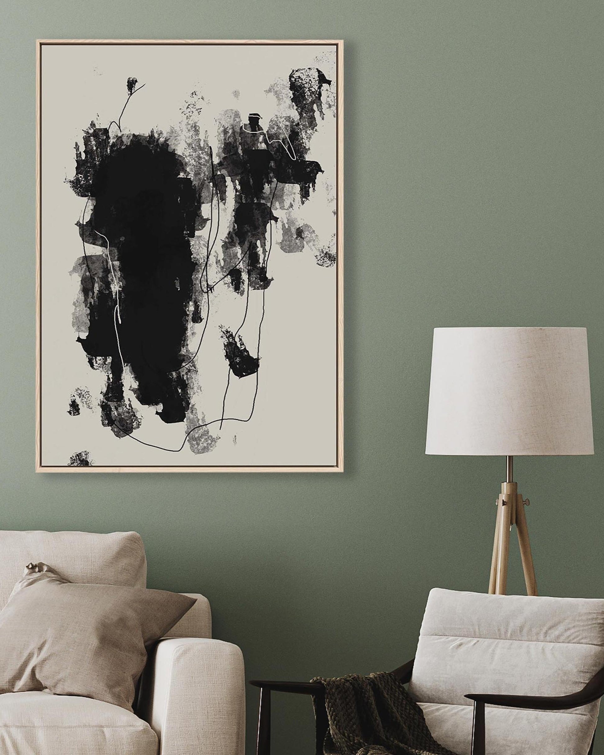 Abstract black and white painting on a green wall above a beige sofa and chair.