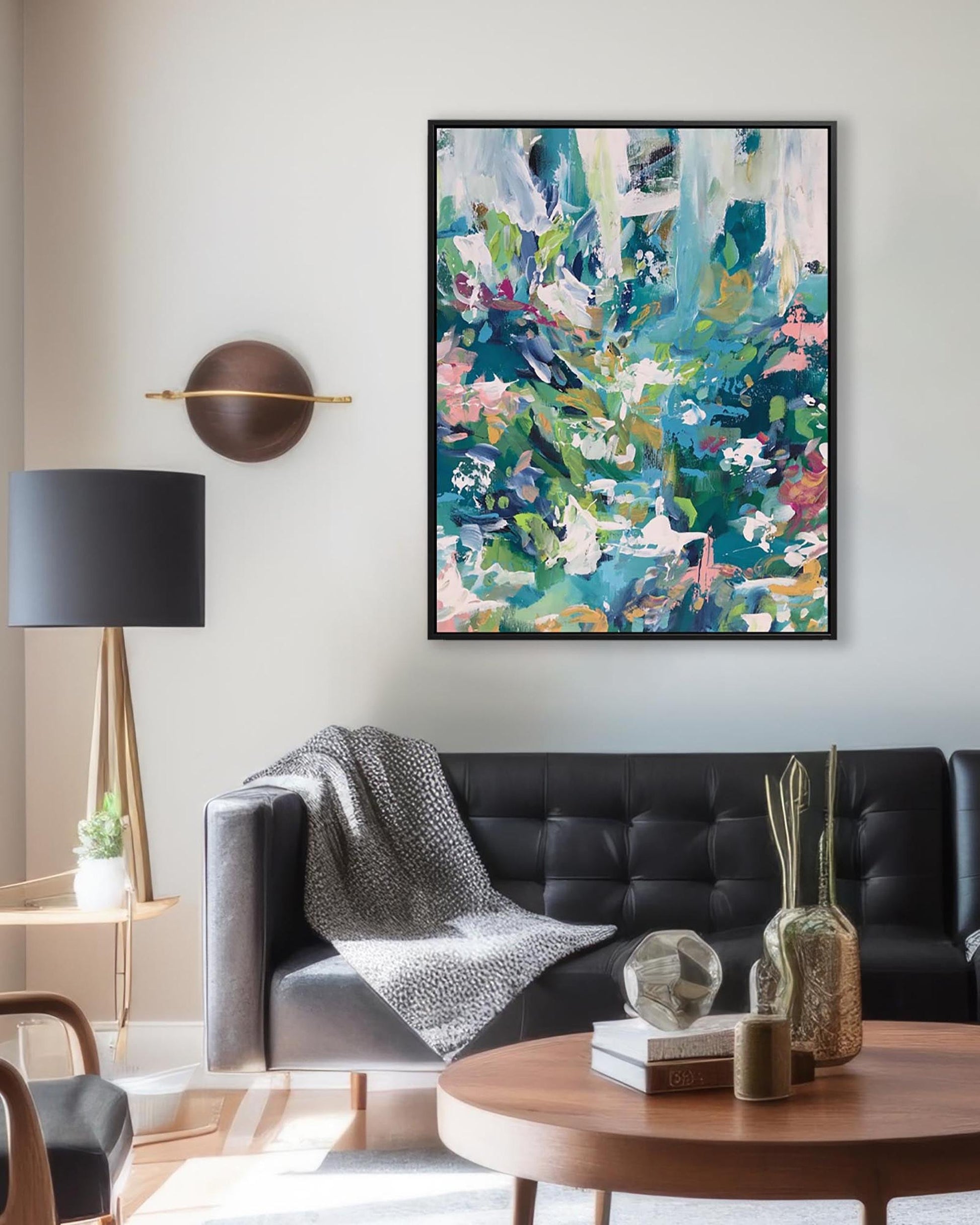 Living room with a black sofa, abstract art on the wall, and decorative items.