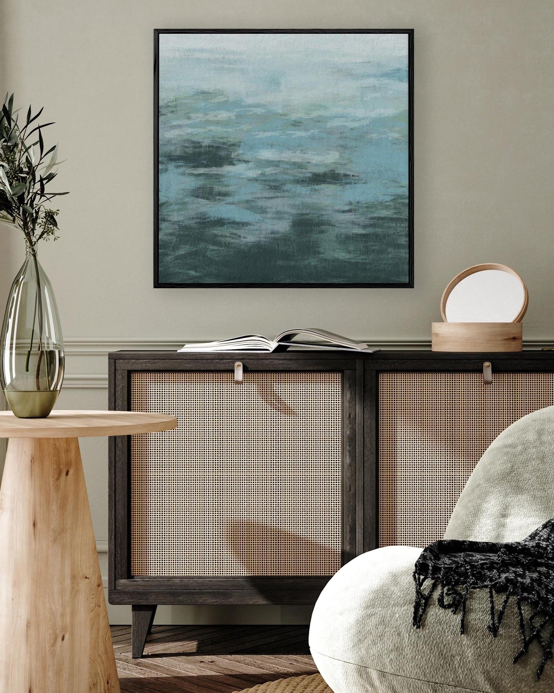 Modern living room with a wooden side table, abstract painting, and armchair.