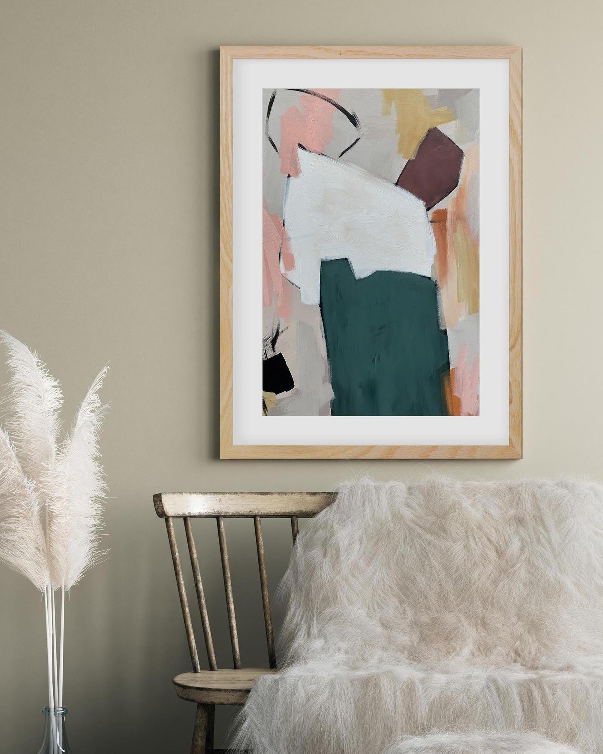 Abstract art print in a wooden frame on a wall with decorative elements below.