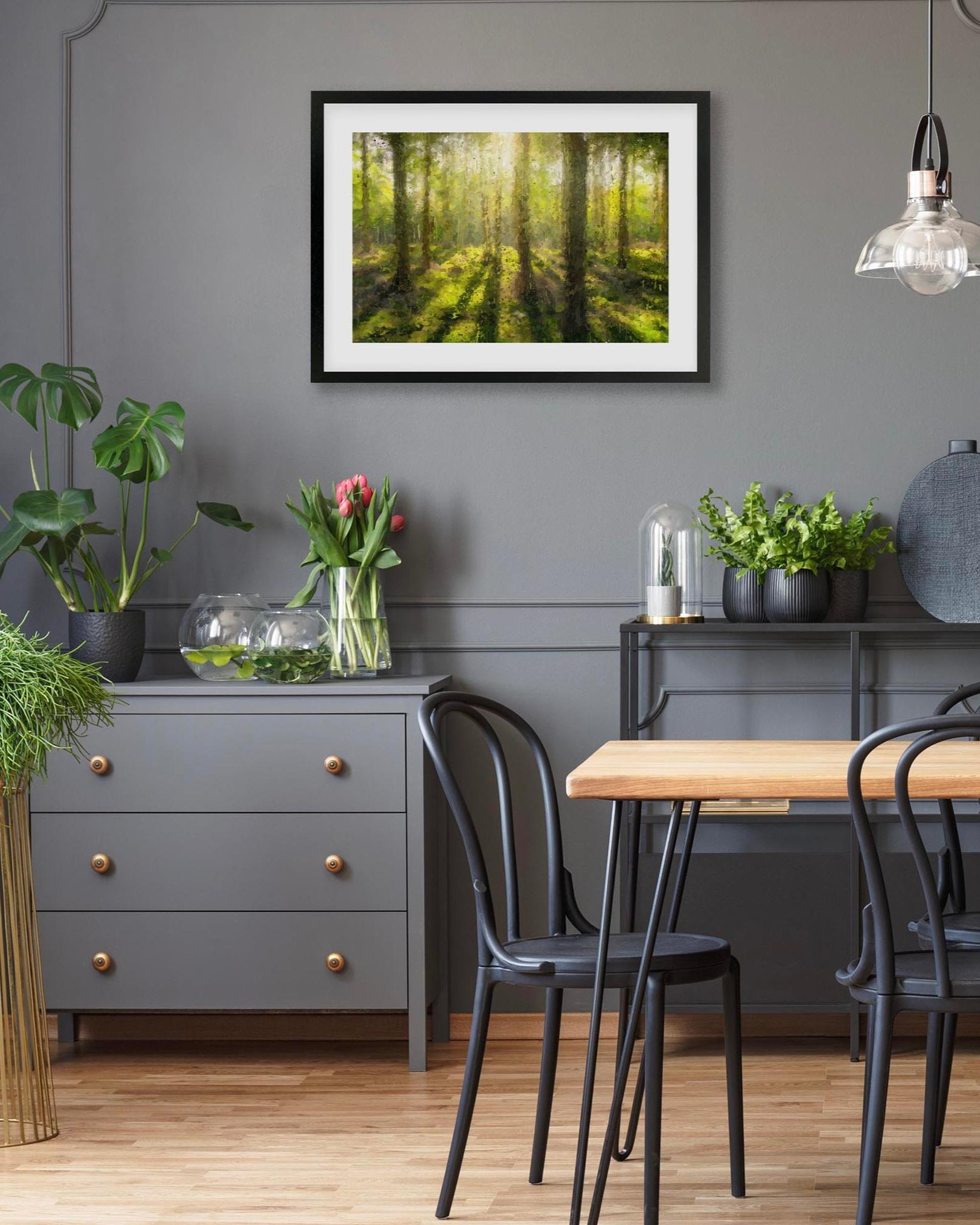 Dining room with a gray wall, framed forest picture, and a wooden table.