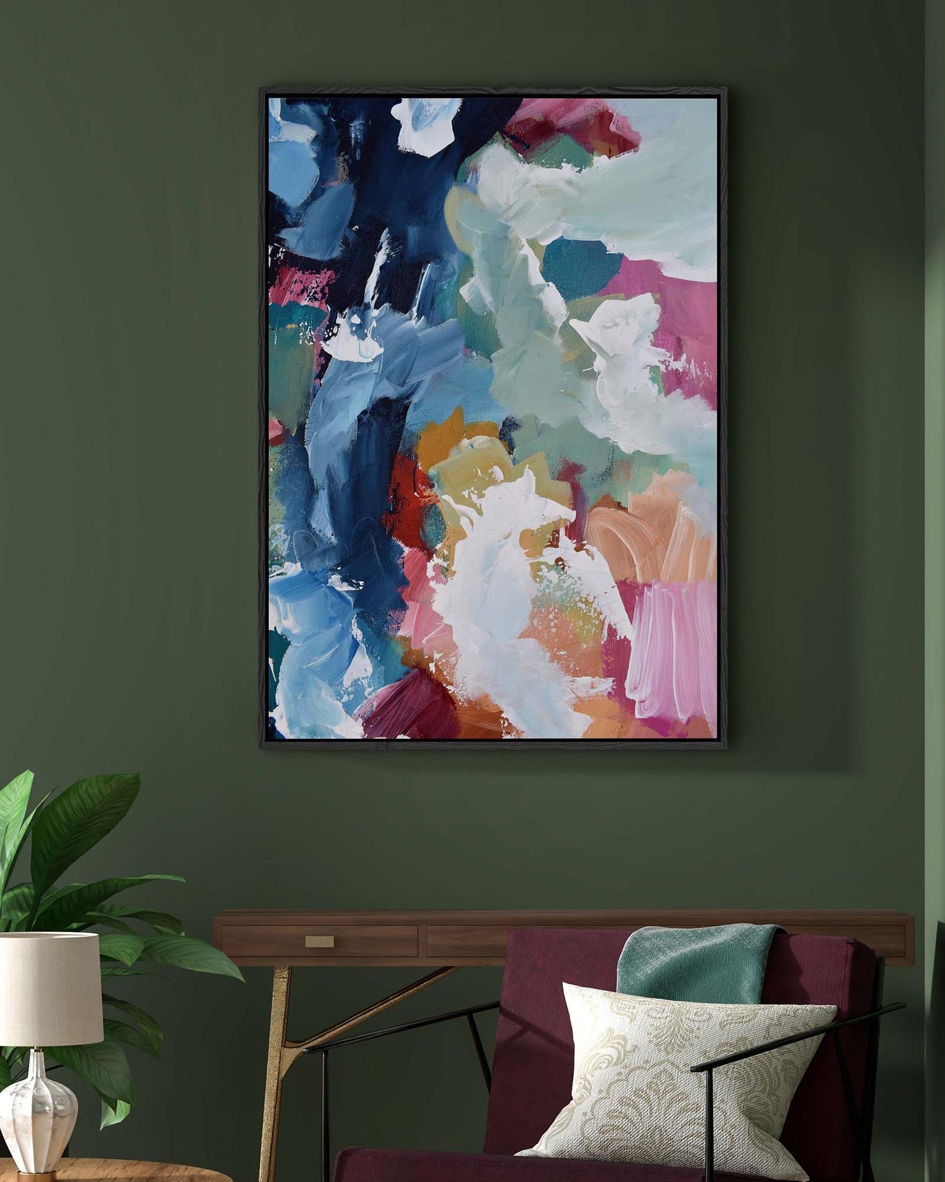 Colorful abstract painting on a dark green wall above a sofa with decorative pillows.