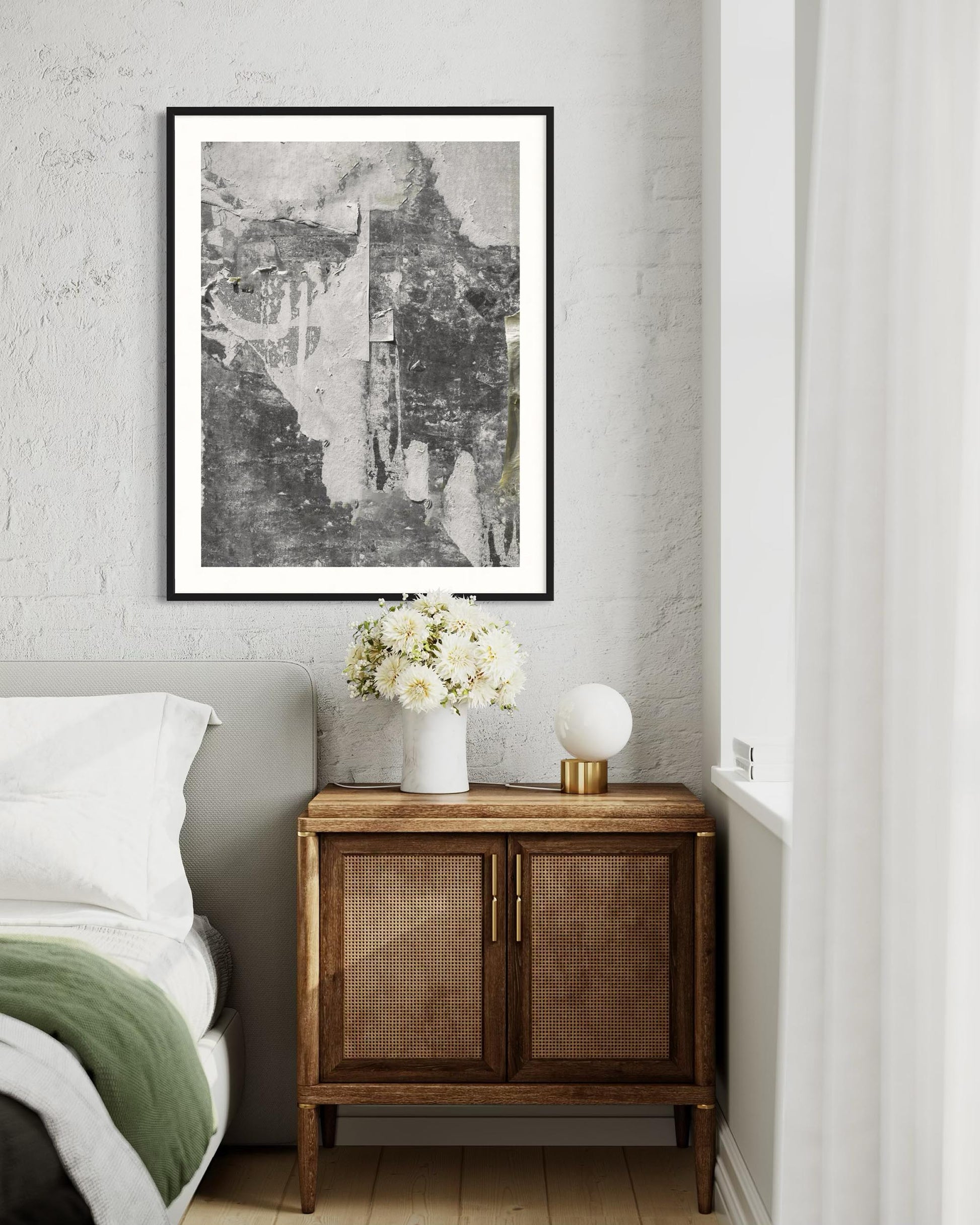 Nursery room with a wooden cabinet, white flowers in a vase, and framed artwork on the wall.