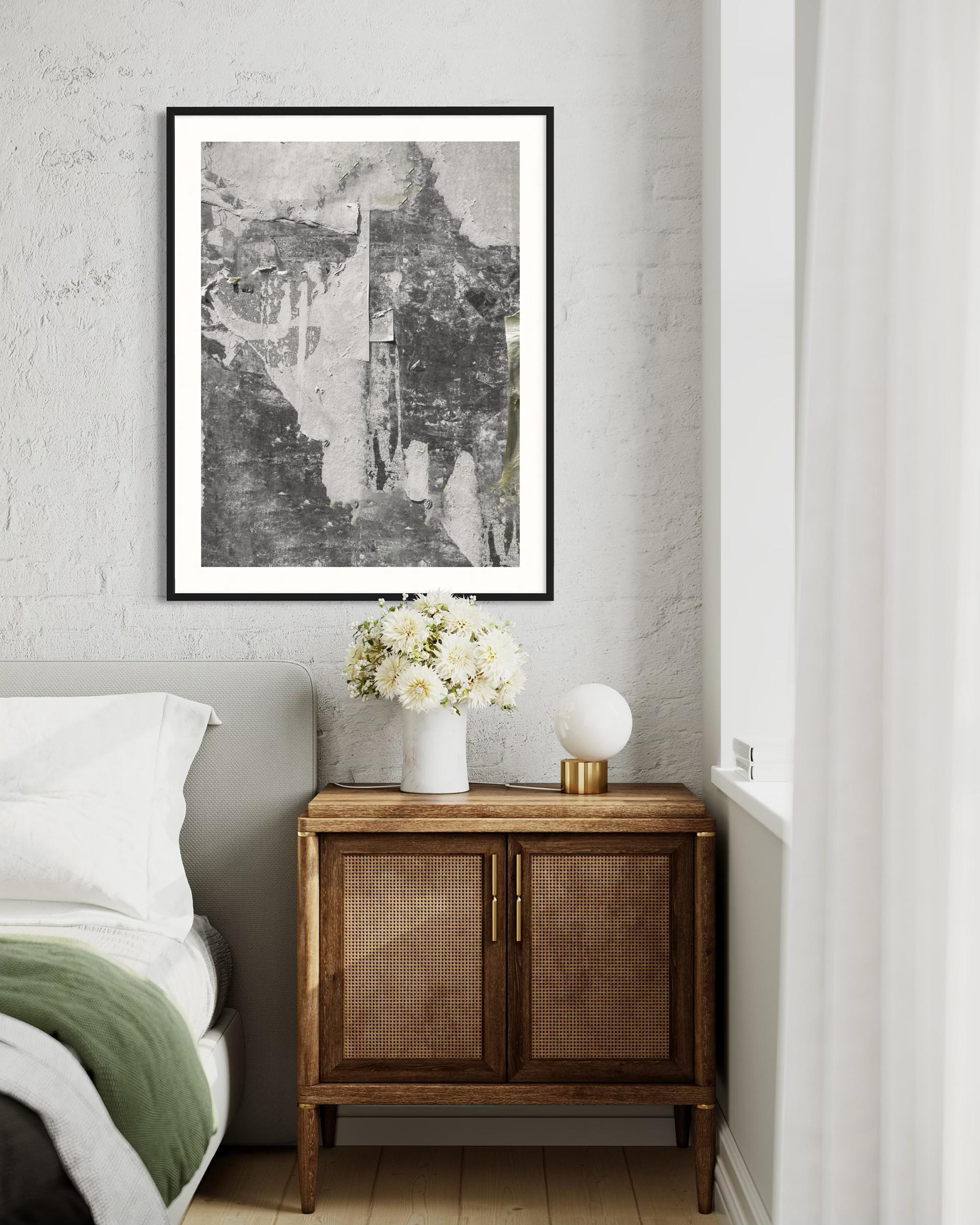Nursery room with a wooden cabinet, white flowers in a vase, and framed artwork on the wall.