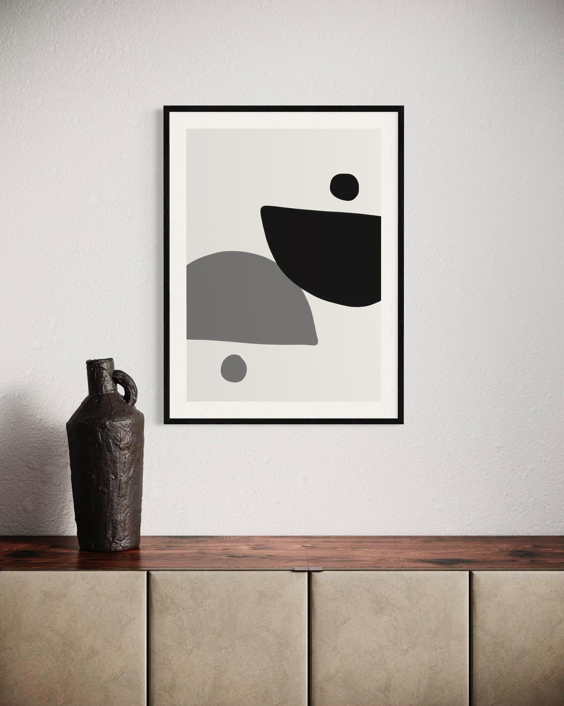 Abstract art print with geometric shapes on a wall above a wooden shelf with a vase.
