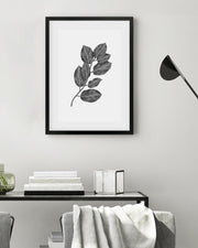 Framed black and white leaf print on a wall above a console table.