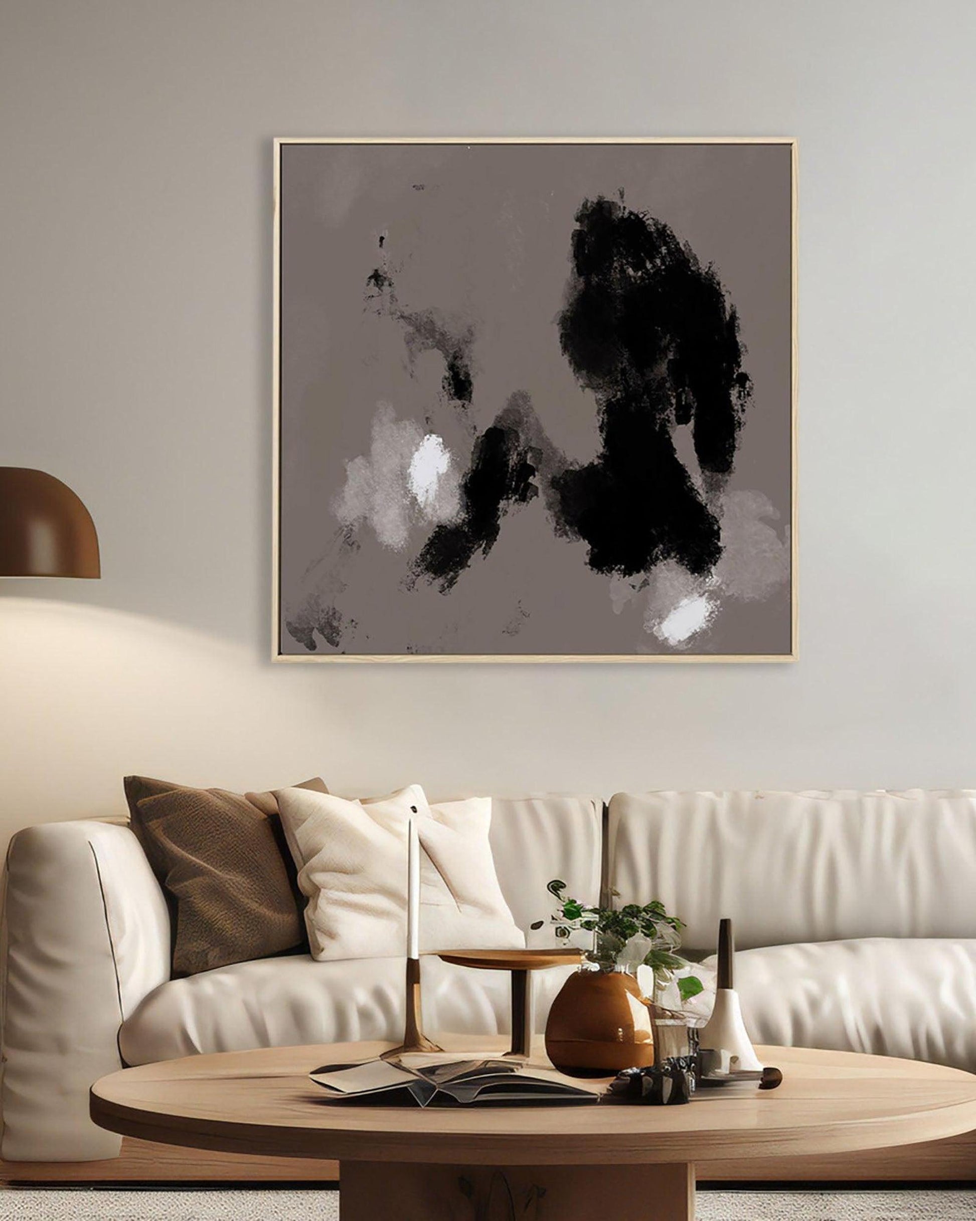 Abstract black and white painting on a wall above a beige sofa with decorative items.