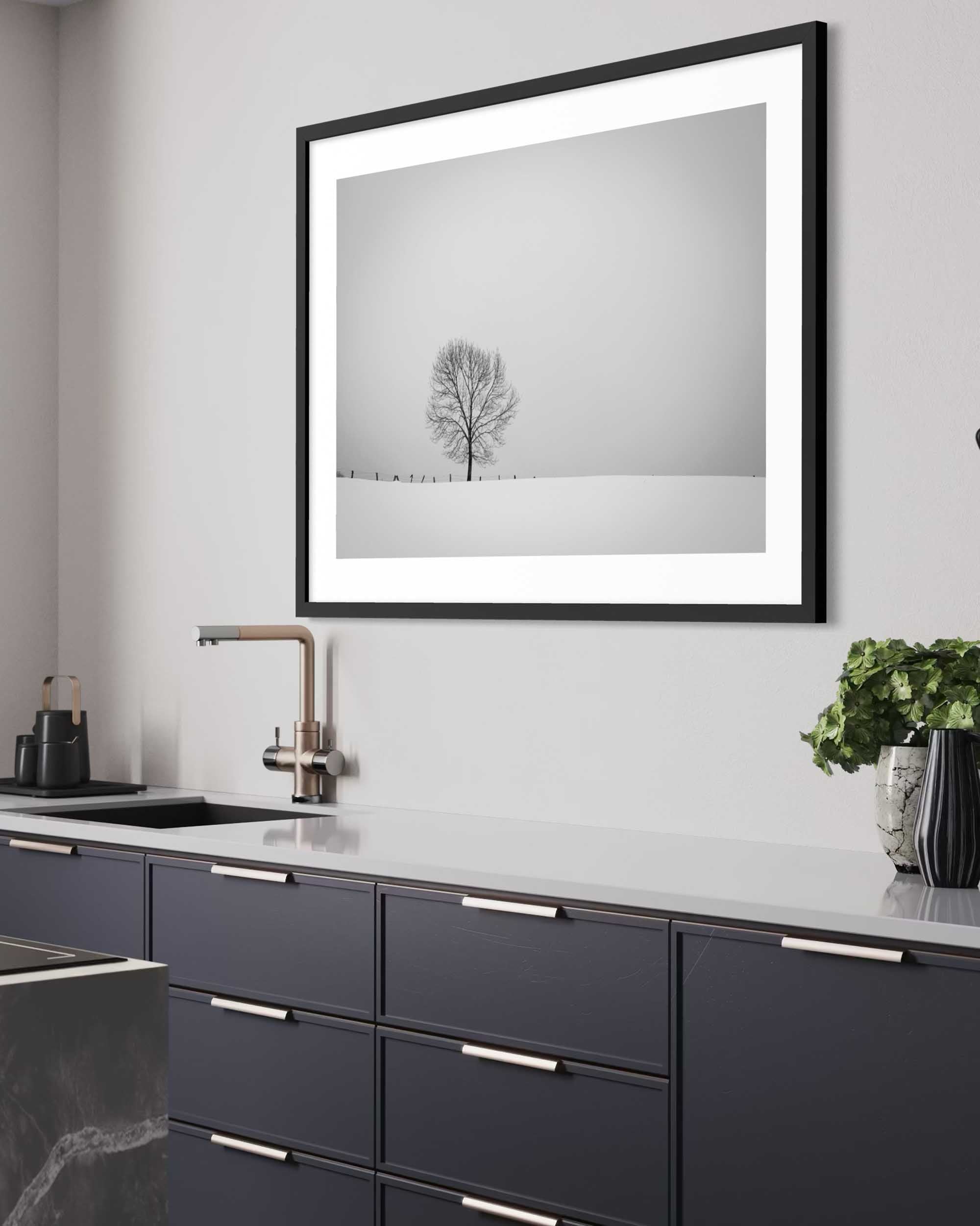 Framed black and white artwork of a tree on a gray wall above a kitchen counter.