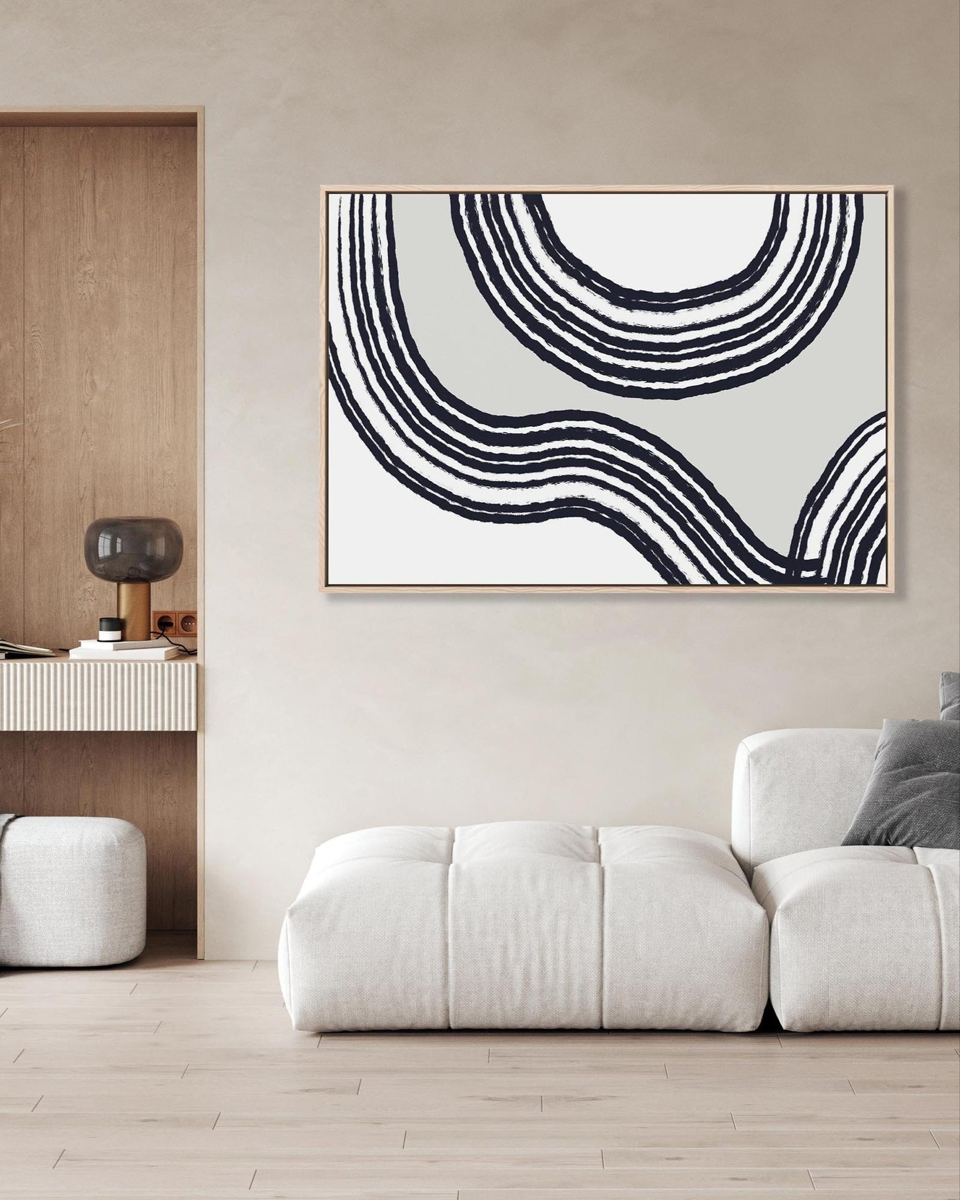 Abstract black and white circular artwork on a wall above a white sofa in a modern living room.