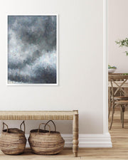 Framed abstract art piece on a wall above a wooden bench with woven baskets.