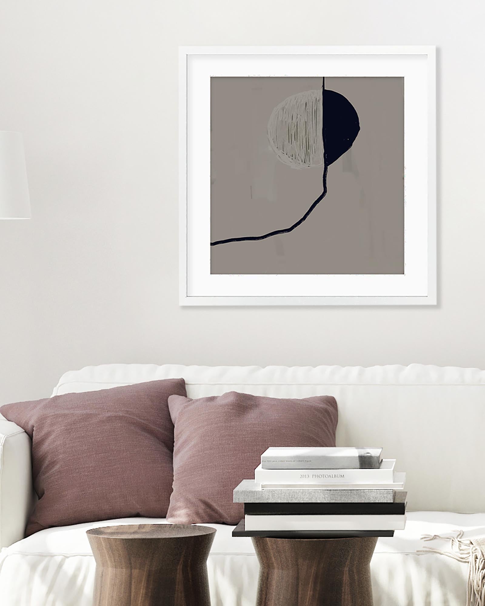 Framed abstract art piece on a wall above a sofa with cushions.