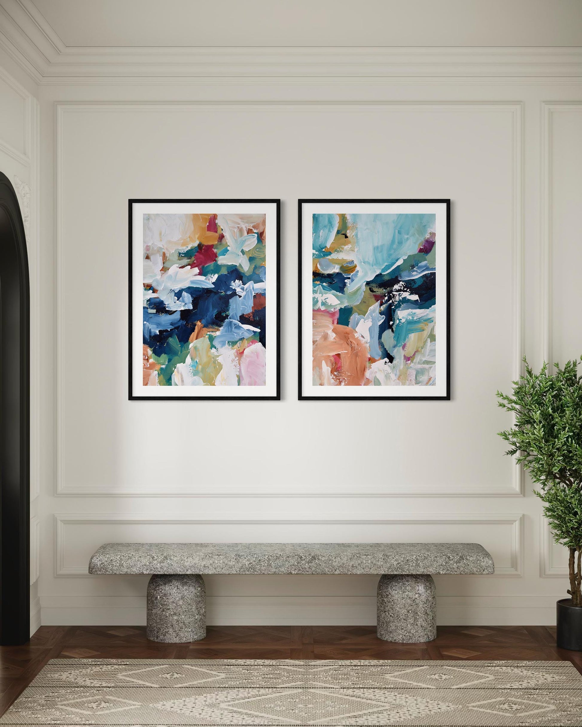 Two abstract art pieces on a wall above a stone bench with a plant to the side.