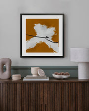Framed abstract art piece on a wall above a wooden console table with decorative items.