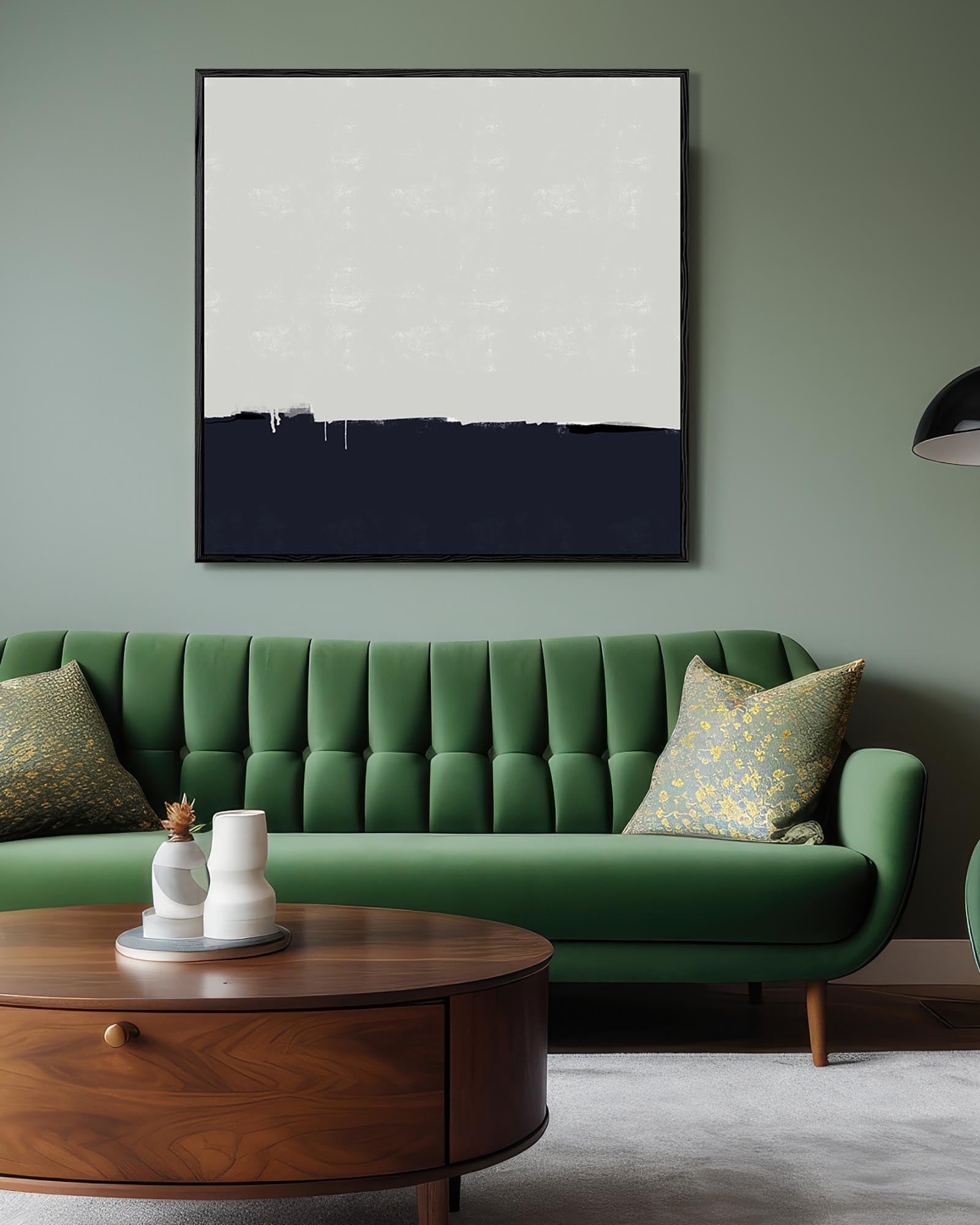 Green sofa in a living room with a framed abstract painting on the wall.