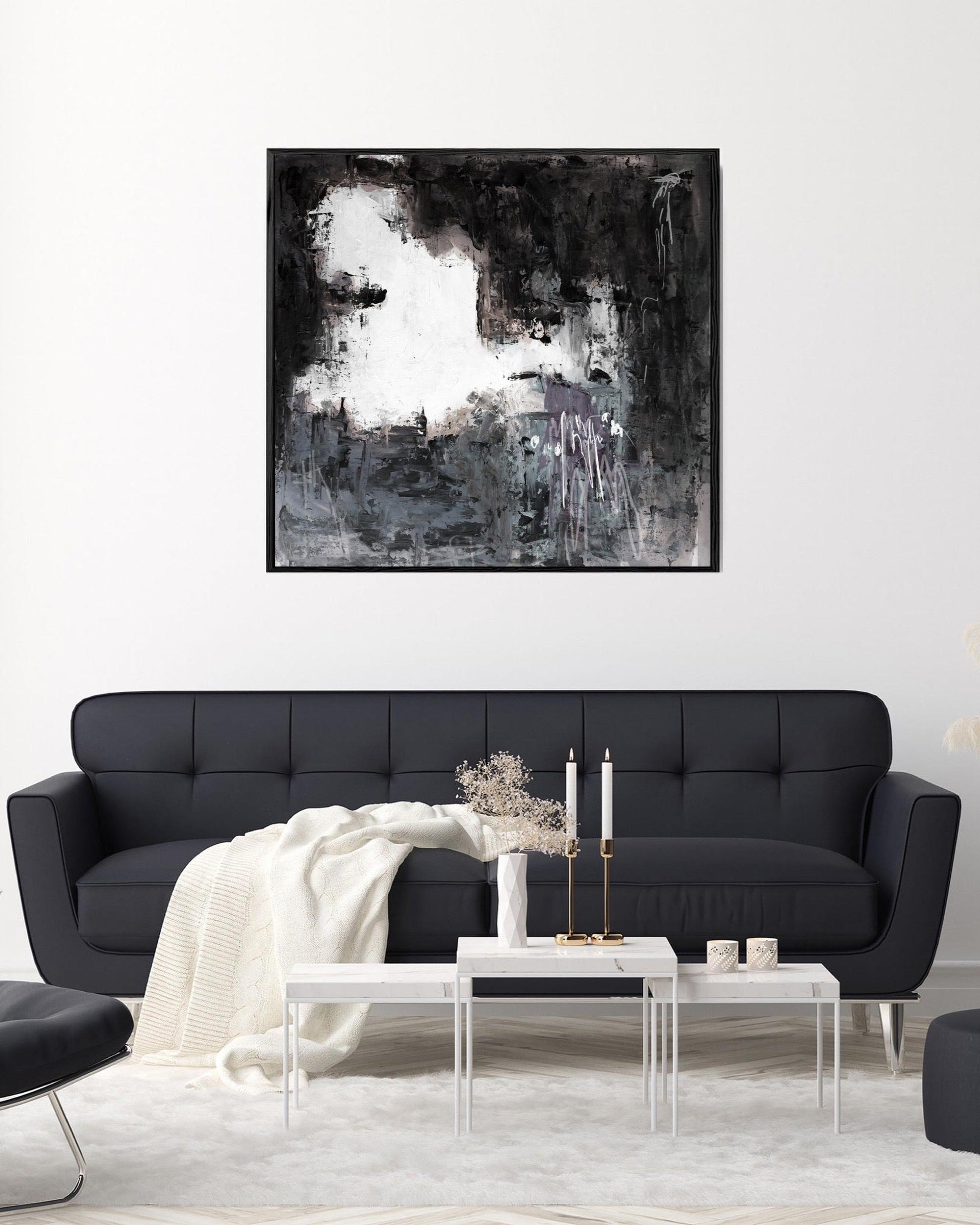 Modern living room with a black sofa, abstract painting, and decorative items.