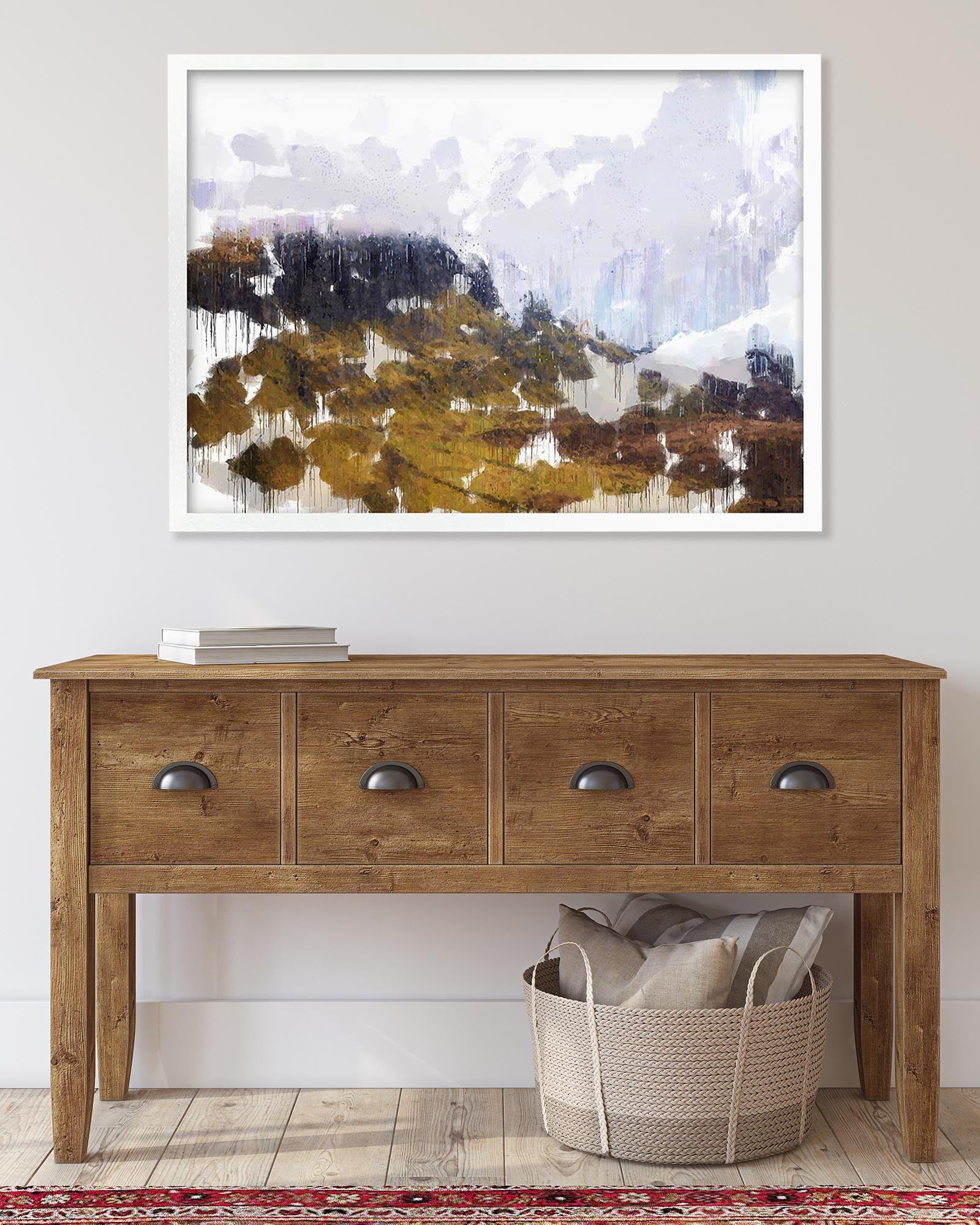 Wooden console table with a basket and books underneath, featuring a framed abstract landscape painting above.