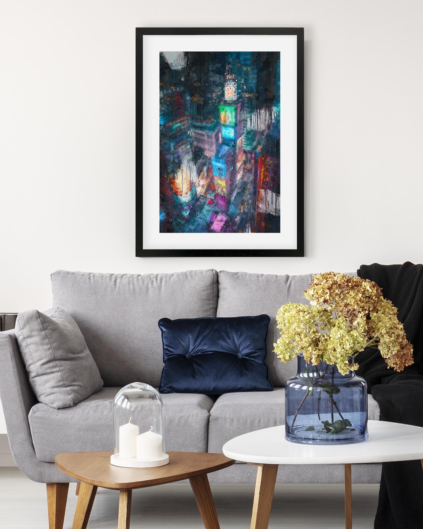 Framed abstract art piece above a gray sofa with decorative elements.