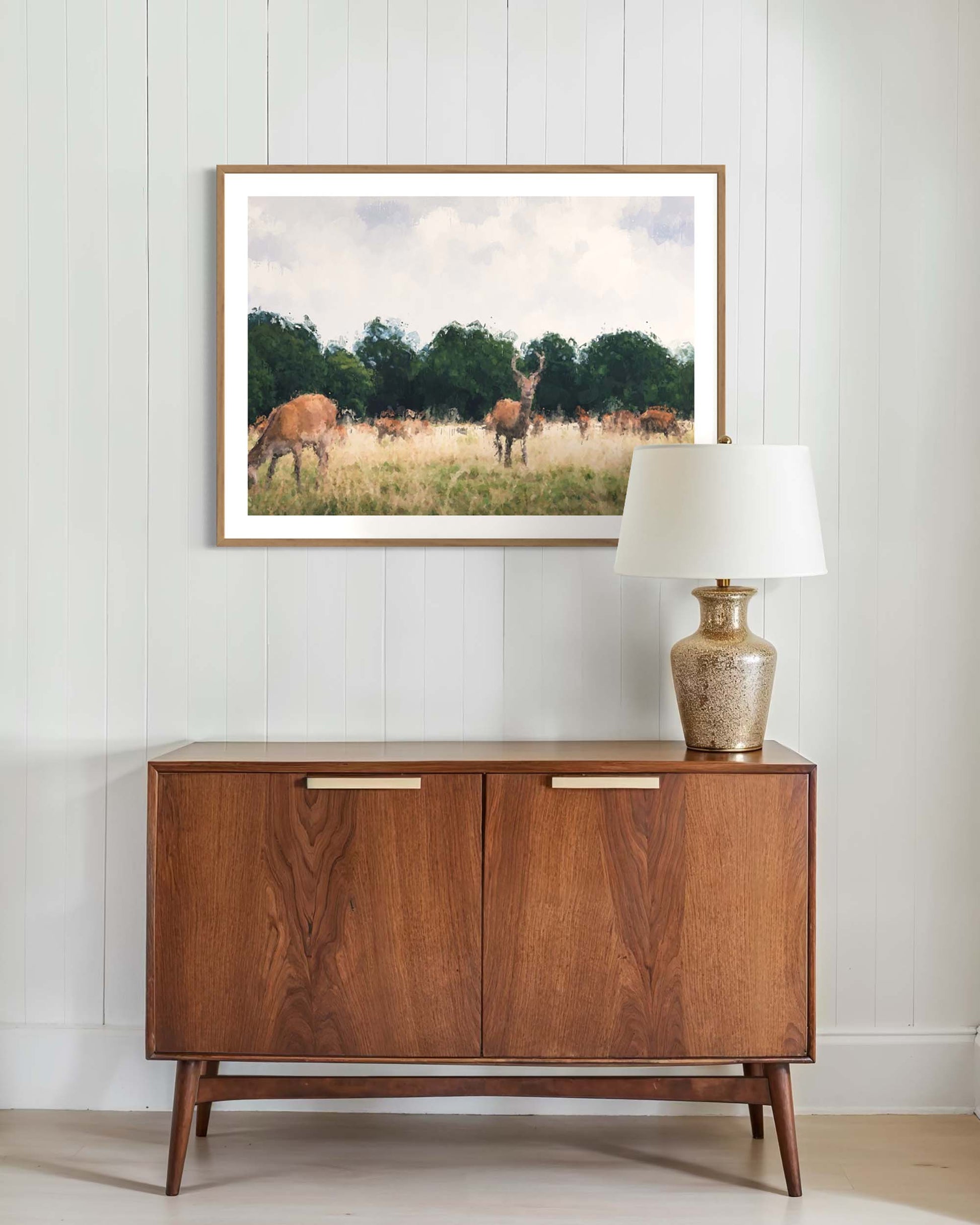 Wooden sideboard with a lamp and framed picture on a white wall